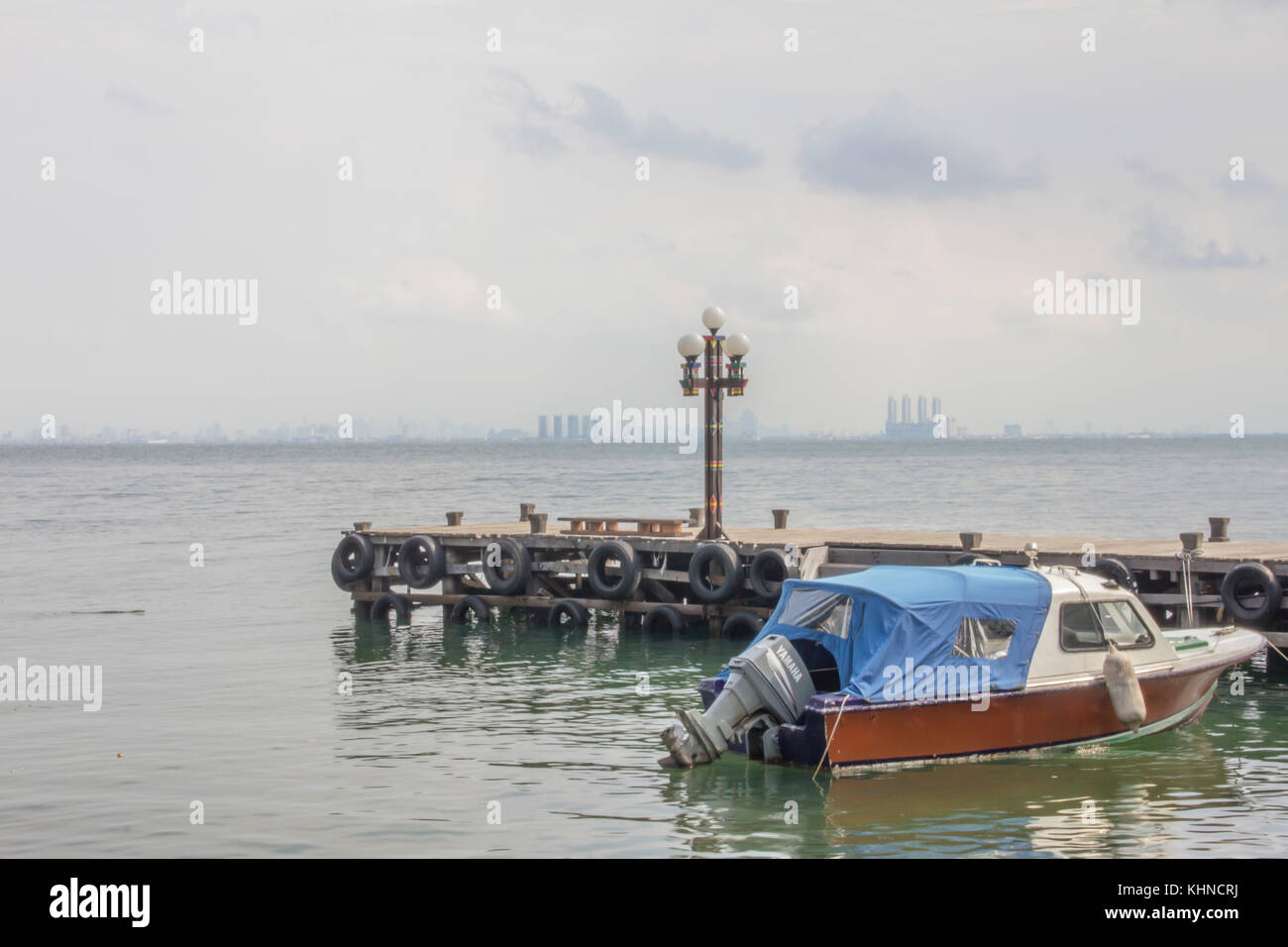 Un dock, un lampione e una barca Foto Stock