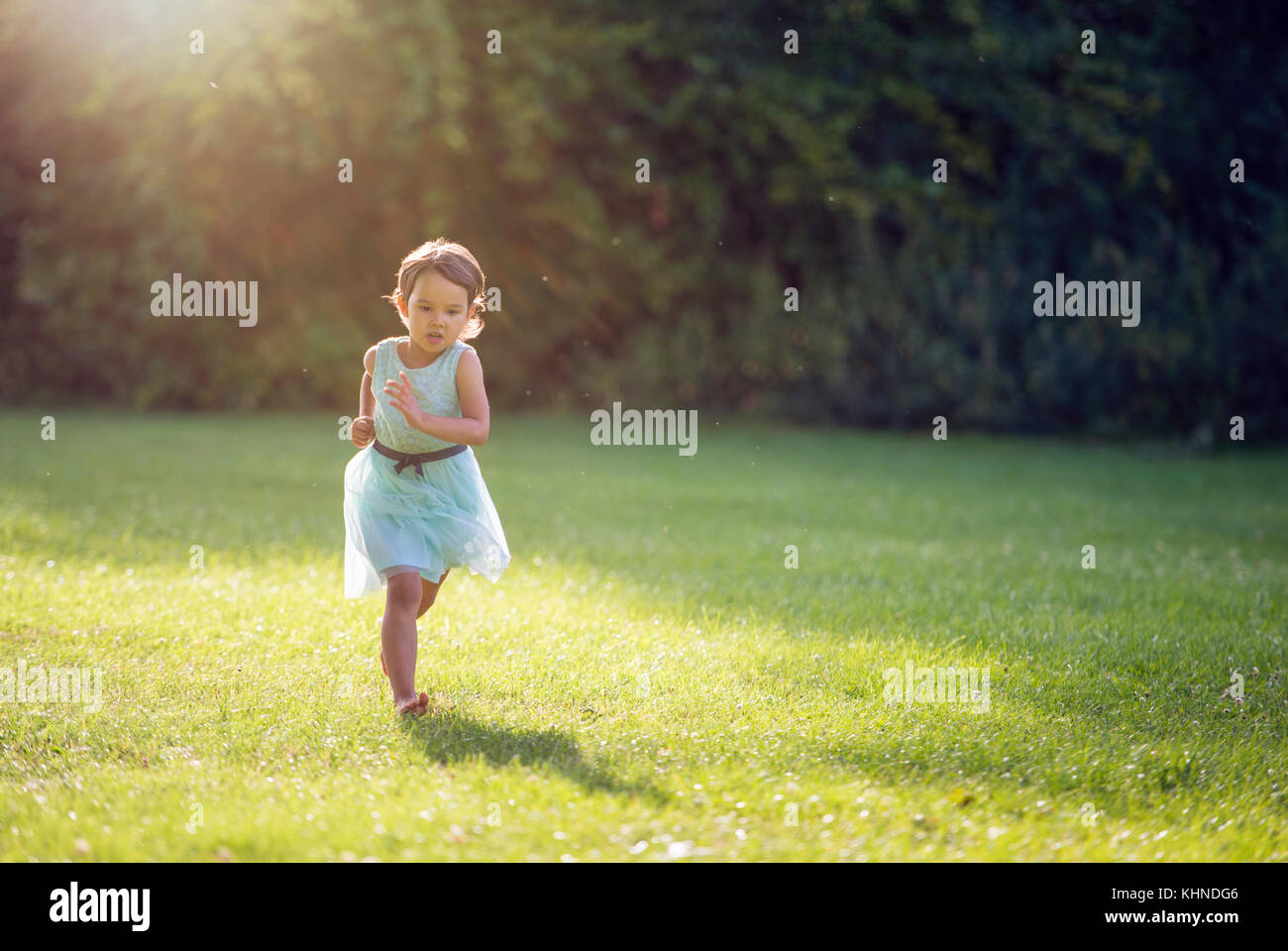 Bambina in esecuzione nel parco con senza scarpe sull'erba Foto Stock