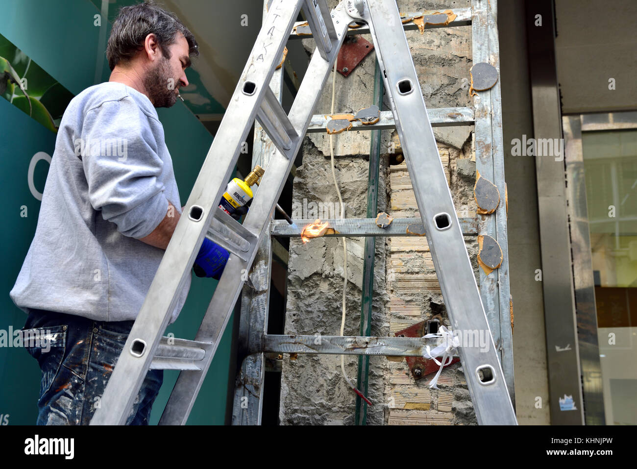 Workman sulla scaletta con torcia a gas funzionante Foto Stock