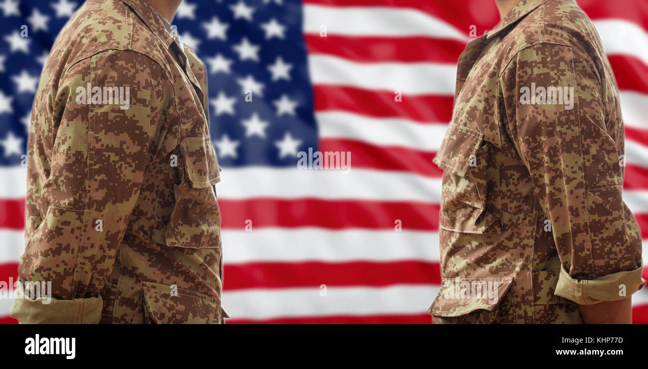 I soldati in militare americano modello digitale di uniformi, in piedi su una bandiera degli stati uniti sullo sfondo Foto Stock