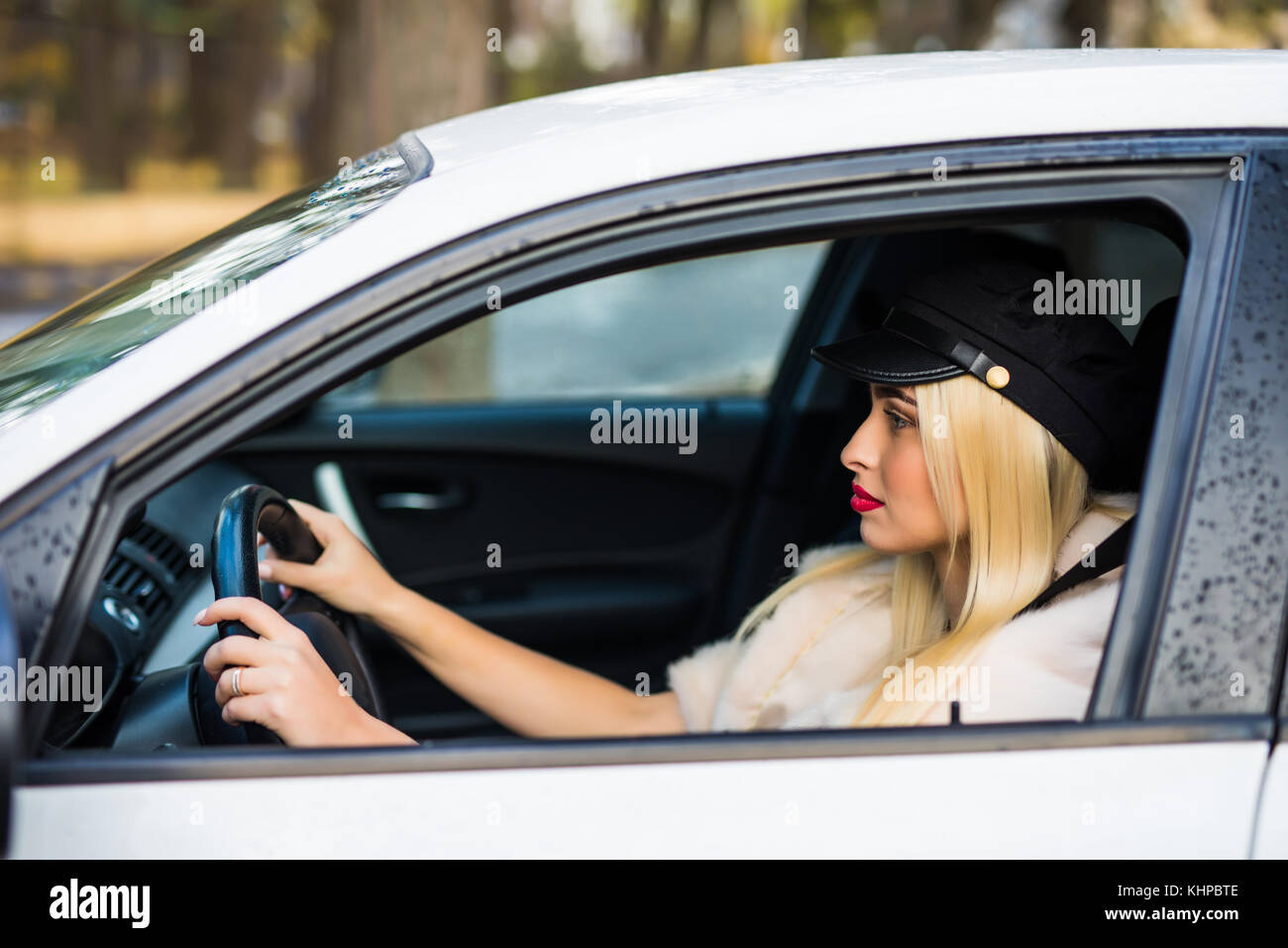 Felice giovane donna seduta nella sua nuova vettura e sorridente Foto Stock