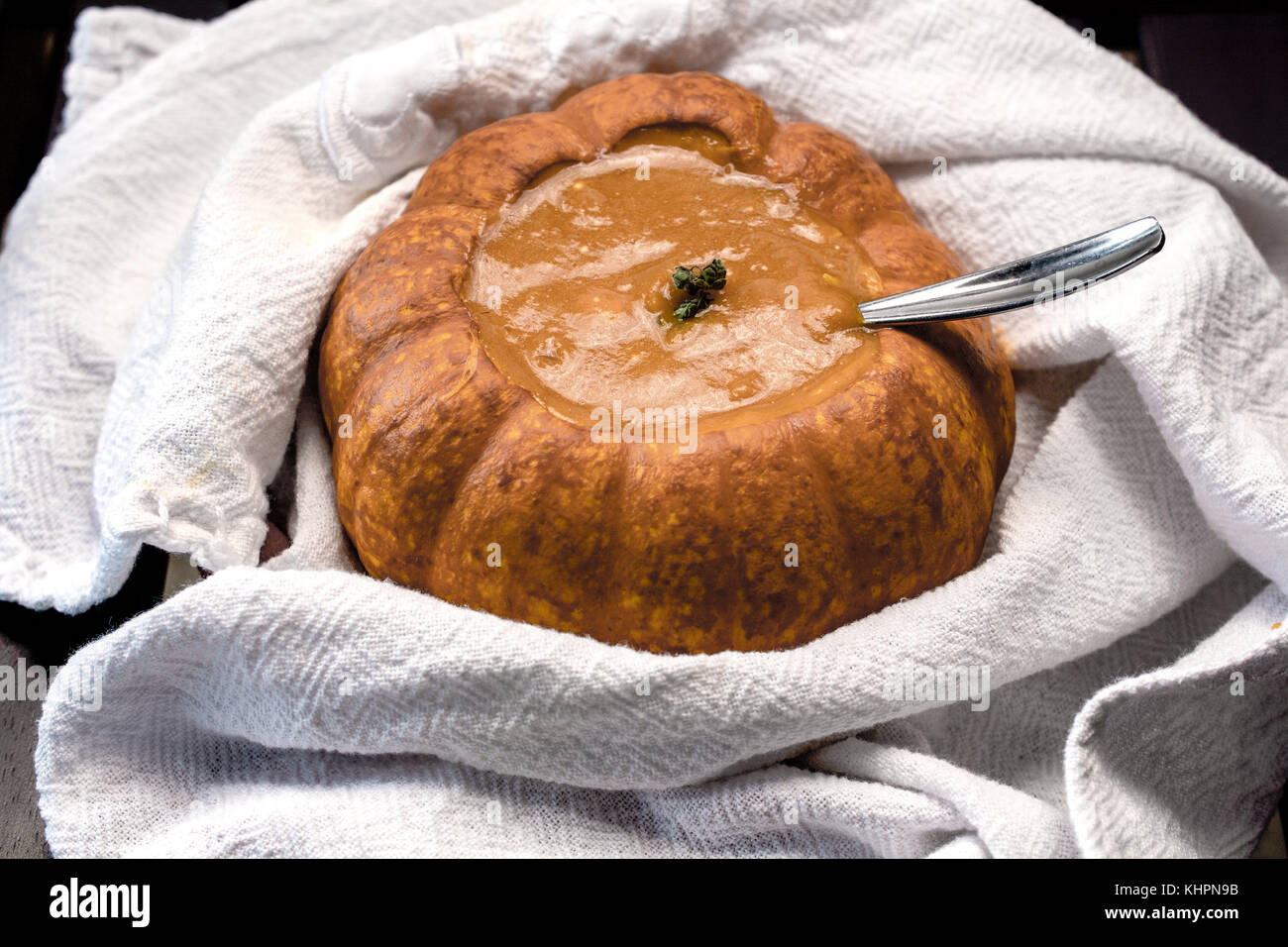 Primo piano sulla zuppa di zucca servito in cotto mini-zucca avvolto in bianco canovaccio su sfondo nero - piatto stagionale Foto Stock