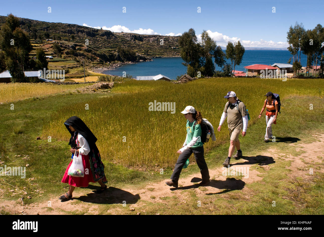 Isola Amantani, lago Titicaca, Puno, Perù. Una donna locale accompagna i turisti a casa sua. Quando arrivano, e per mezzo di un sistema di rotazione, t Foto Stock