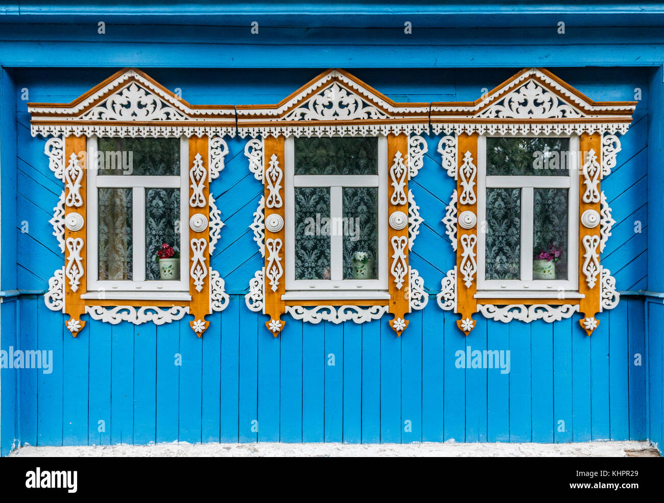 Tre finestre in un blu parete in legno di un tradizionale cottage con ornamenti bianchi su infissi in legno, Suzdal, Russia. Foto Stock