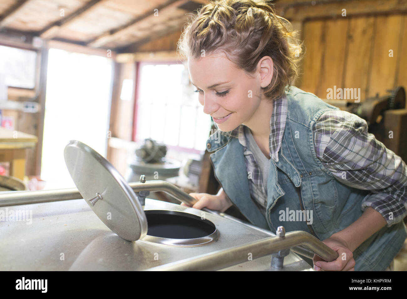 Lavoratore di sesso femminile che aprire il rubinetto sul serbatoio in campo industriale-workshop Foto Stock