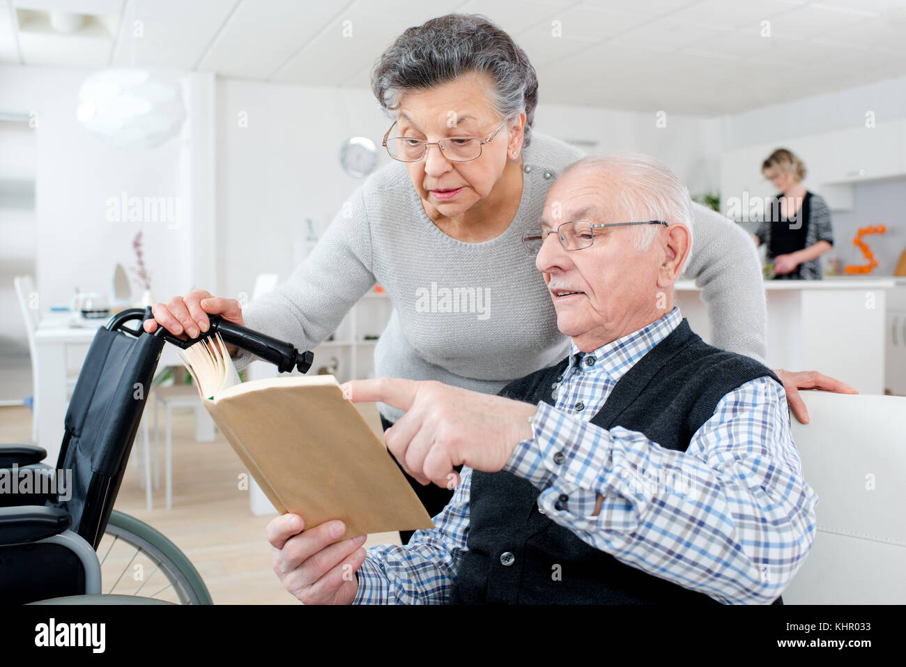 Senior adulto giovane controllando un opuscolo a casa Foto Stock