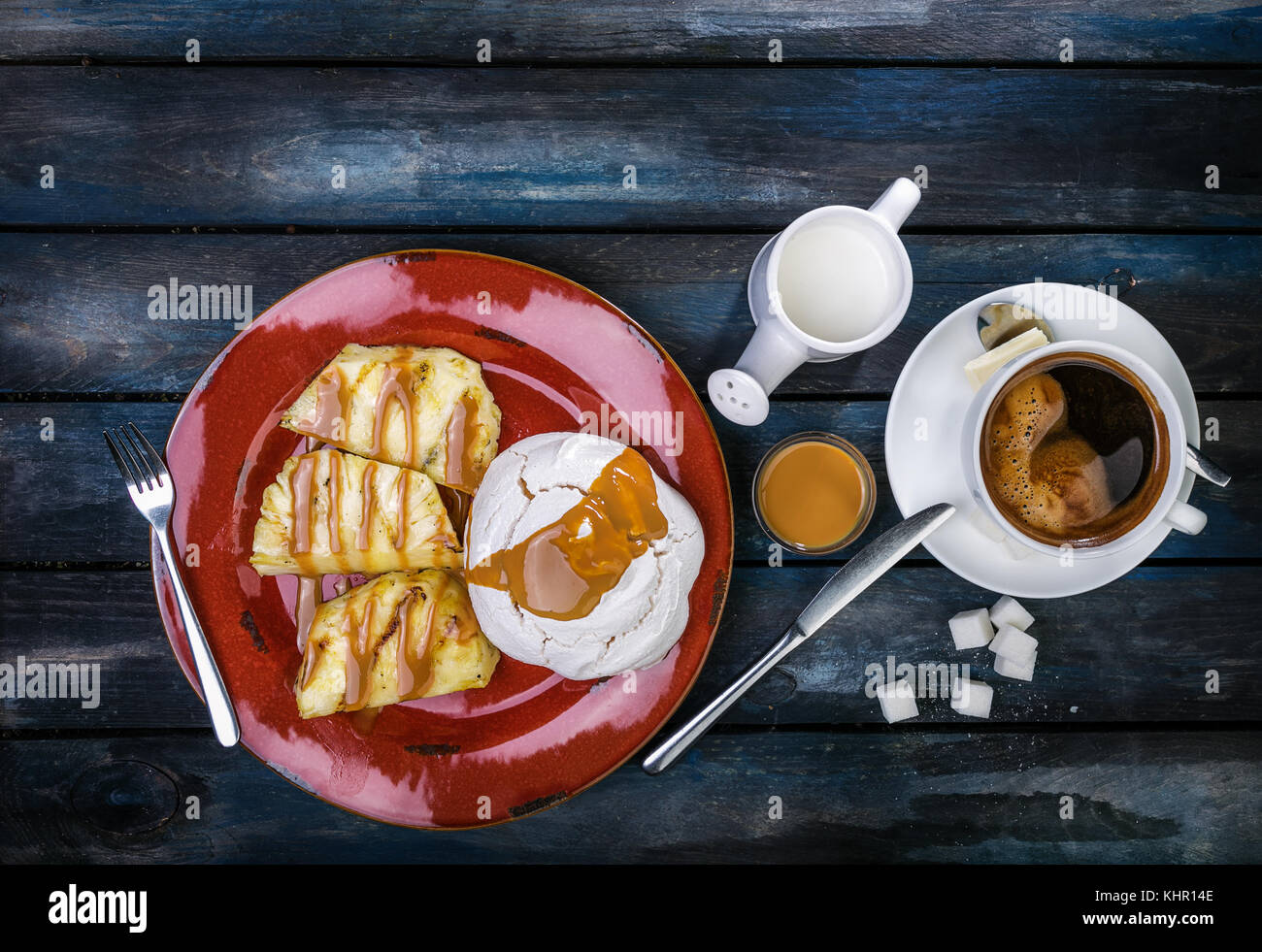 Deliziosi dessert. meringa con ananas e caffè fresco su un colore di sfondo di legno. vista dall'alto. Foto Stock