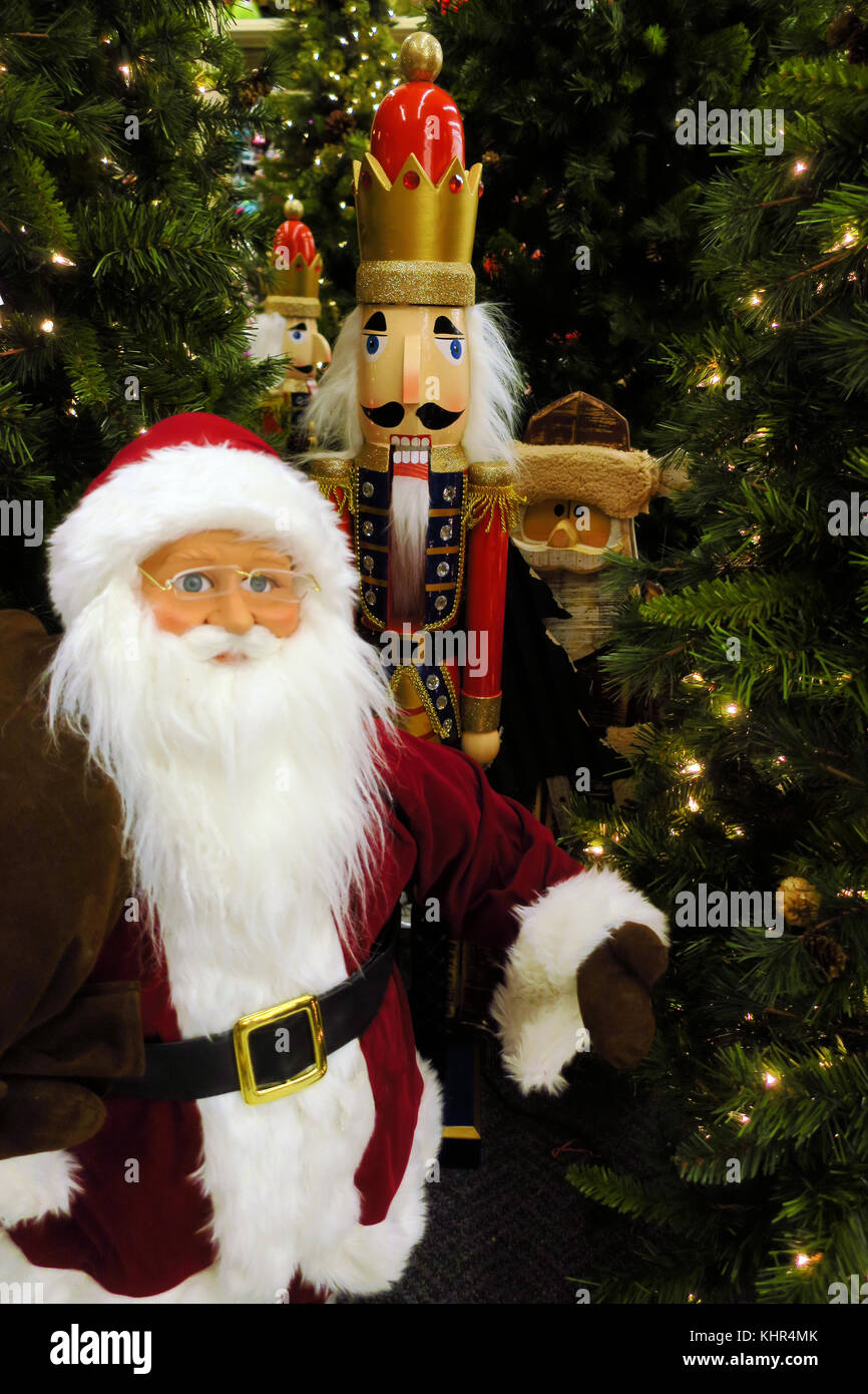 Santa, lo schiaccianoci e un elfo in piedi accanto a illuminato di alberi di Natale. Foto Stock