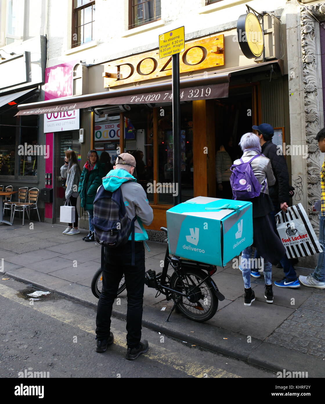 Deliveroo ciclista colecting ordinare cibo dal ristorante a Londra in Inghilterra Foto Stock