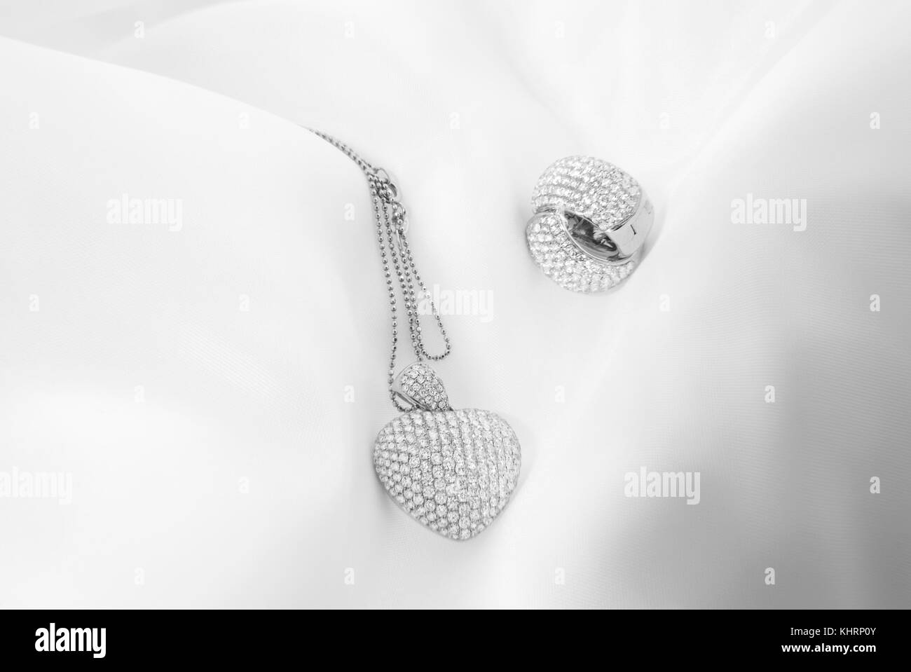 Orecchini in oro bianco a forma di cuore Collana con diamanti bianchi su morbido sfondo sfocato Foto Stock
