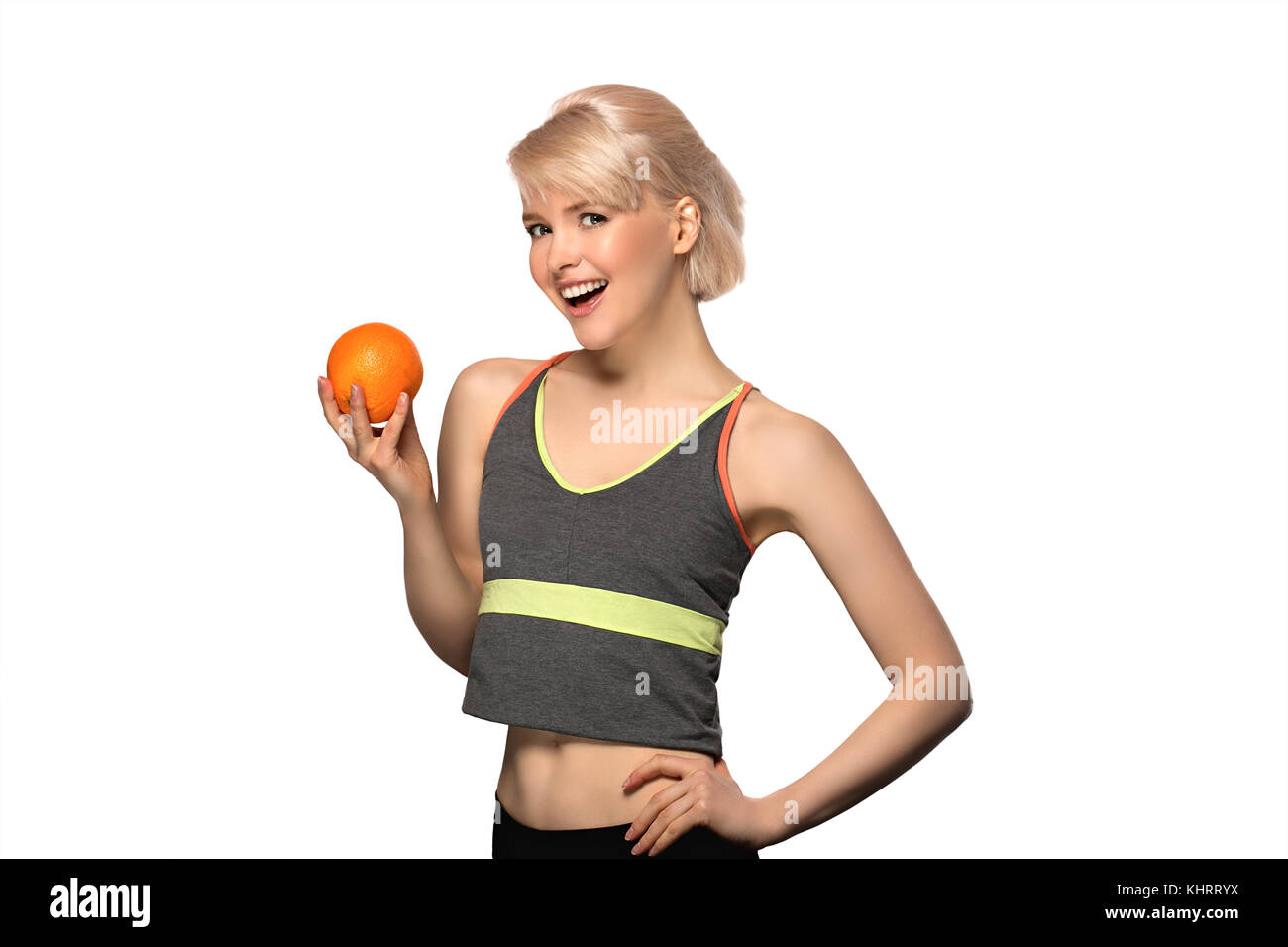 Sorridenti slim donna tenendo l'arancione, ritratto in studio isolato su sfondo bianco, uno stile di vita sano concetto Foto Stock