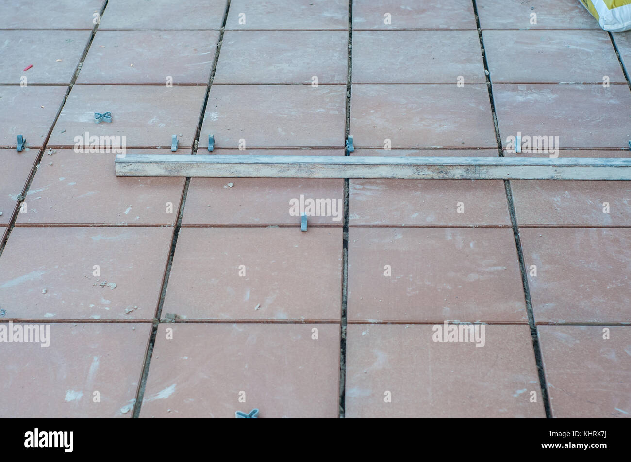 Installazione di piastrelle su un pavimento per terrazzo e alcuni pezzi di plastica con forma a croce per lasciare spazio tra le piastrelle Foto Stock