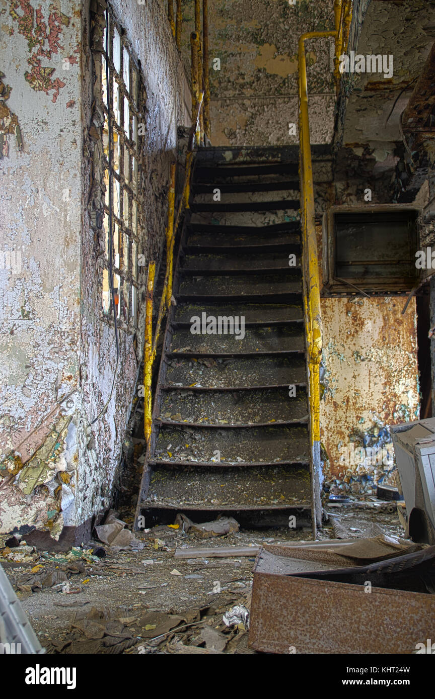Scale con ringhiera gialla in una rovina industrial interior. abbandonata vecchia fabbrica. Foto Stock
