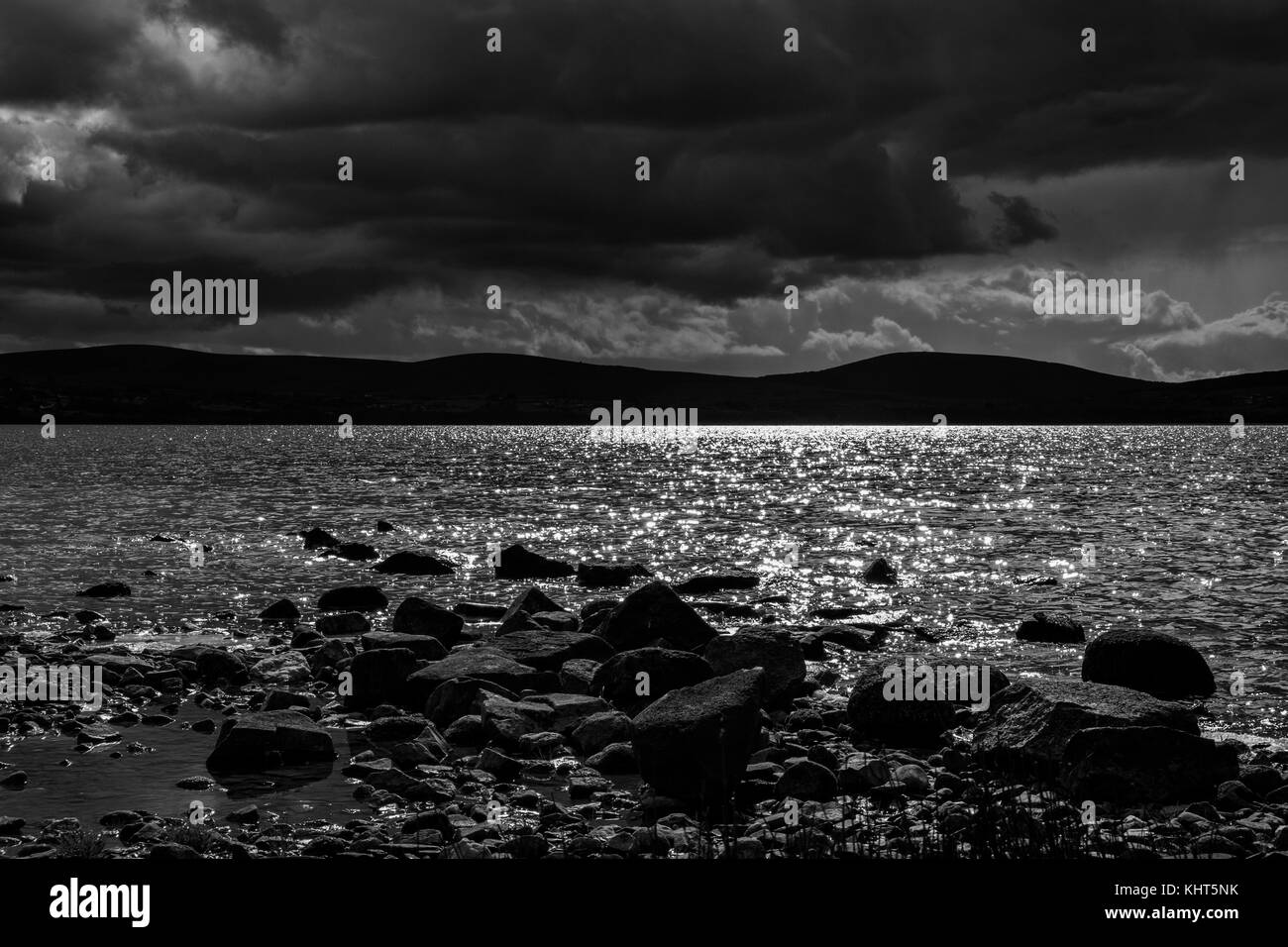 Il nero e il bianco paesaggio guardando sopra Blessington lakes con pesanti rainclouds e sunshine glinting sull'acqua, County Wicklow, Irlanda Foto Stock