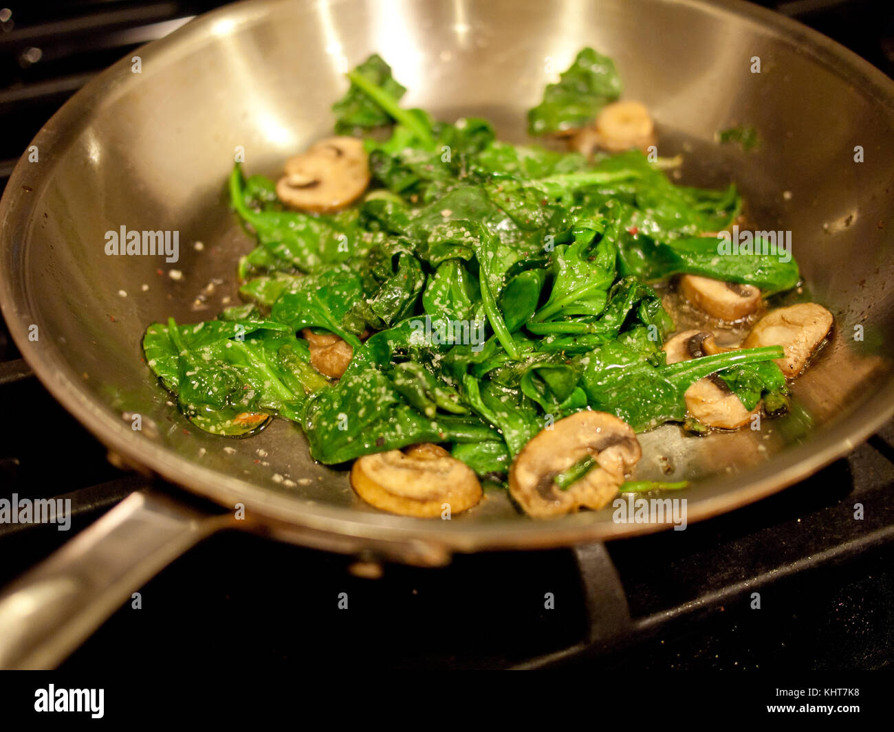 Spinaci e funghi cucinando in una padella Foto Stock