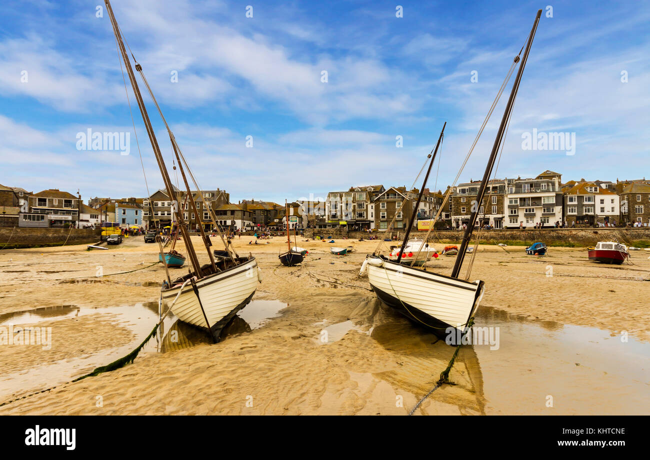 Barche a terra in St Ives Harbour con la bassa marea, guardando verso la città di negozi. Foto Stock