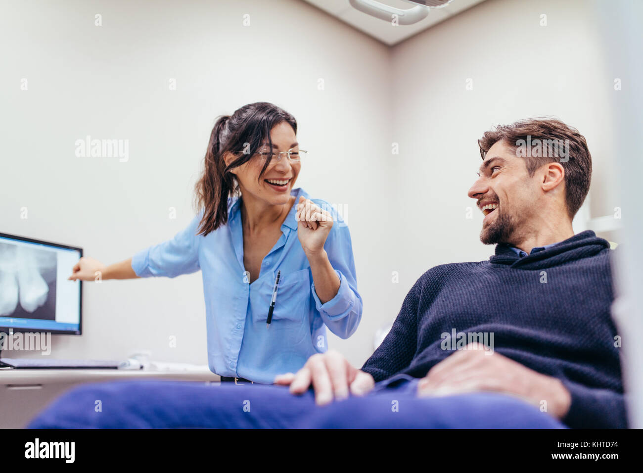 Uomo Donna in visita dal dentista presso la clinica. Paziente di sesso maschile seduto su una sedia a parlare con il dentista e sorridente. Foto Stock