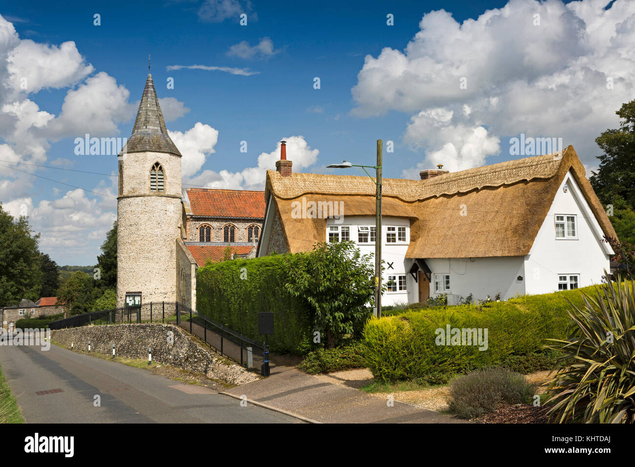 Regno Unito, Inghilterra, Norfolk, la Brecks, Croxton, Chiesa di Tutti i Santi, con torre rotonda accanto a nuovo cottage con il tetto di paglia Foto Stock