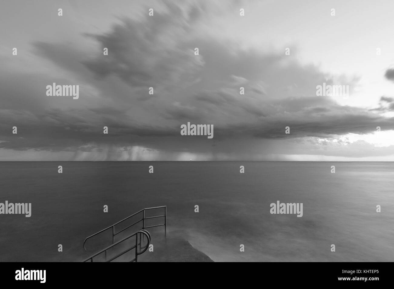 Tempesta di pioggia drammatica seascape con scala bagno sulla costa del mare adriatico, Istria, Croazia. in bianco e nero. Foto Stock