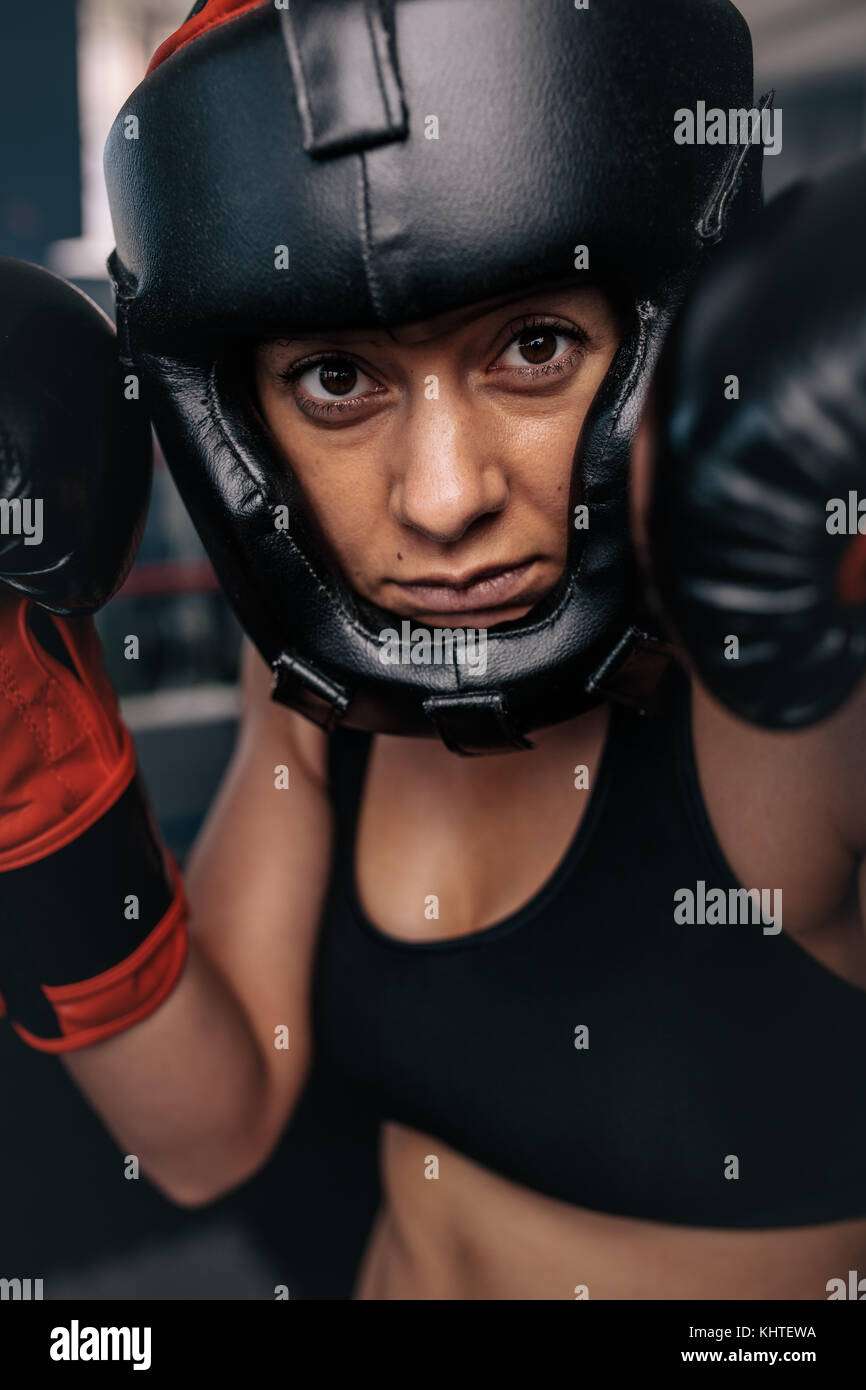 Close up ritratto di un boxer femmina nel suo ingranaggio di inscatolamento. Donna boxer in un boxing studio indossando la protezione della testa e i guantoni. Foto Stock
