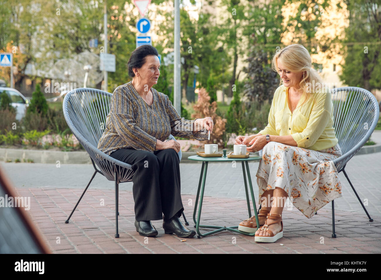 Senior donna seduta in street cafe di bere caffè, parlare, ridere e divertirsi. Le persone felici nel concetto di pensionamento. Foto Stock
