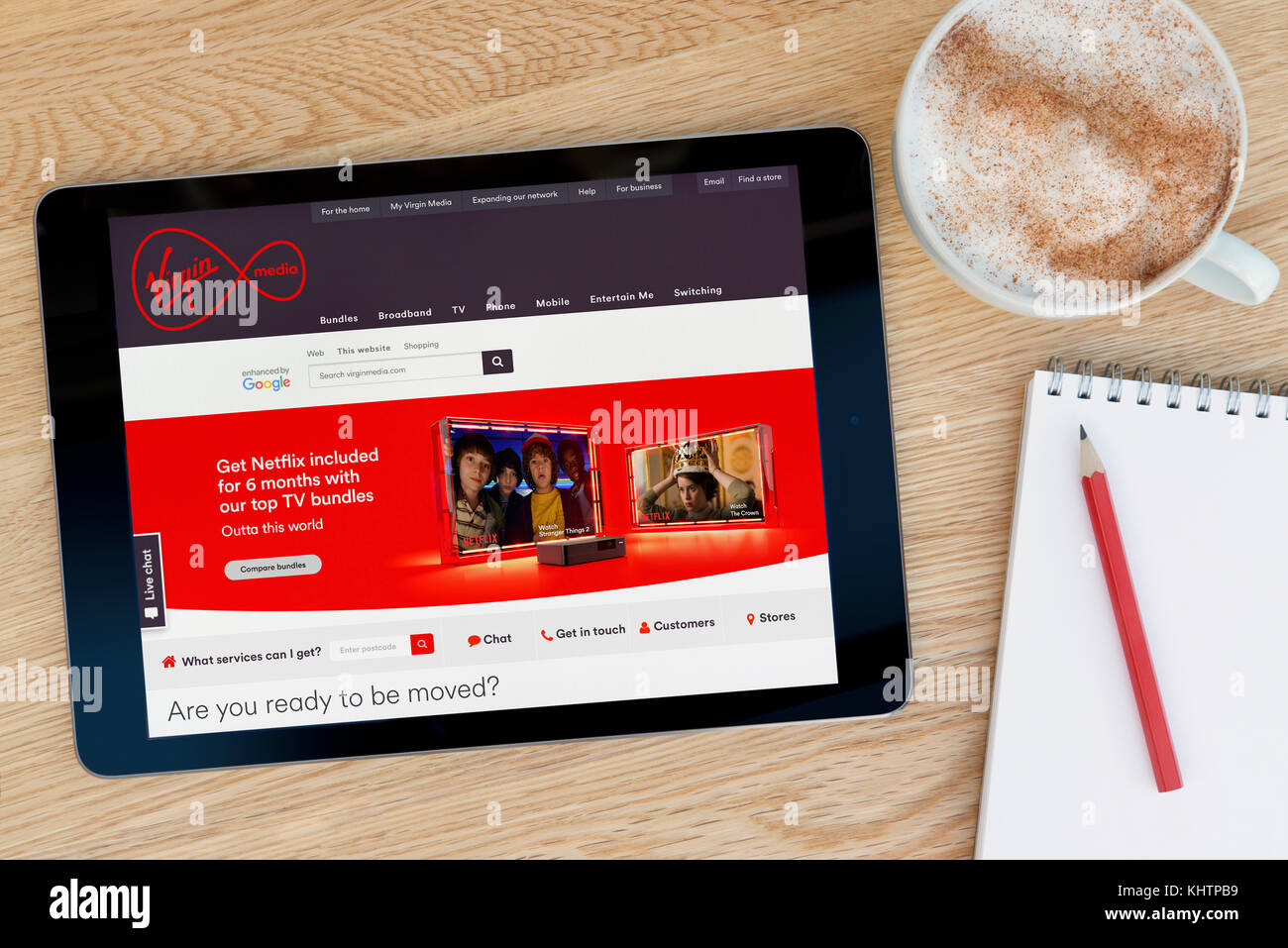 La Virgin Media funzionalità del sito su un iPad dispositivo tablet pc che si appoggia su una tavola di legno accanto a un blocco note e matita e una tazza di caffè (editoriale) Foto Stock