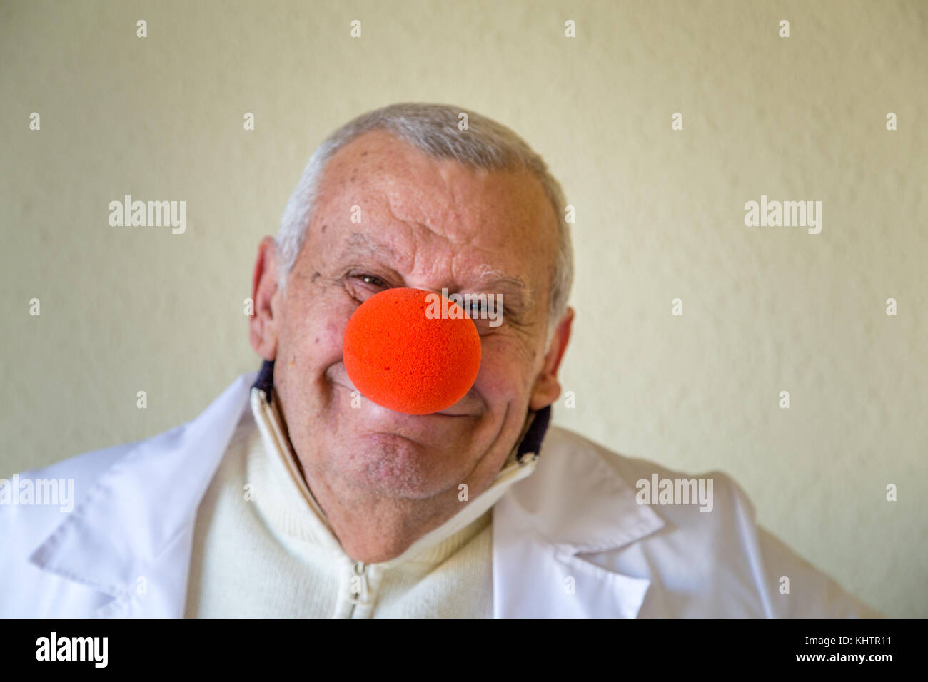 Il vecchio medico di campagna con clown naso rosso sorridente Foto Stock