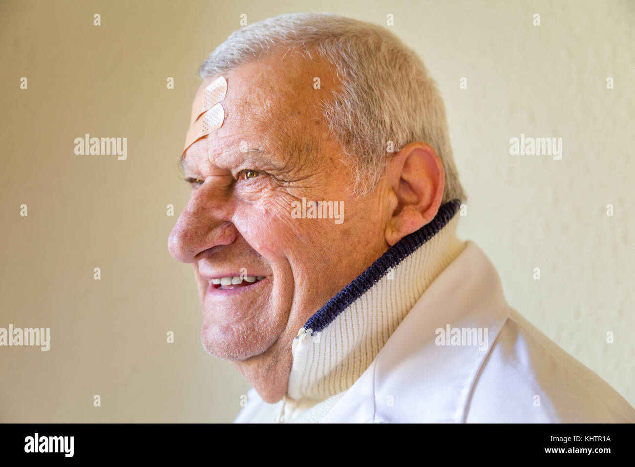 Il vecchio medico con patch sulla fronte sorridente Foto Stock
