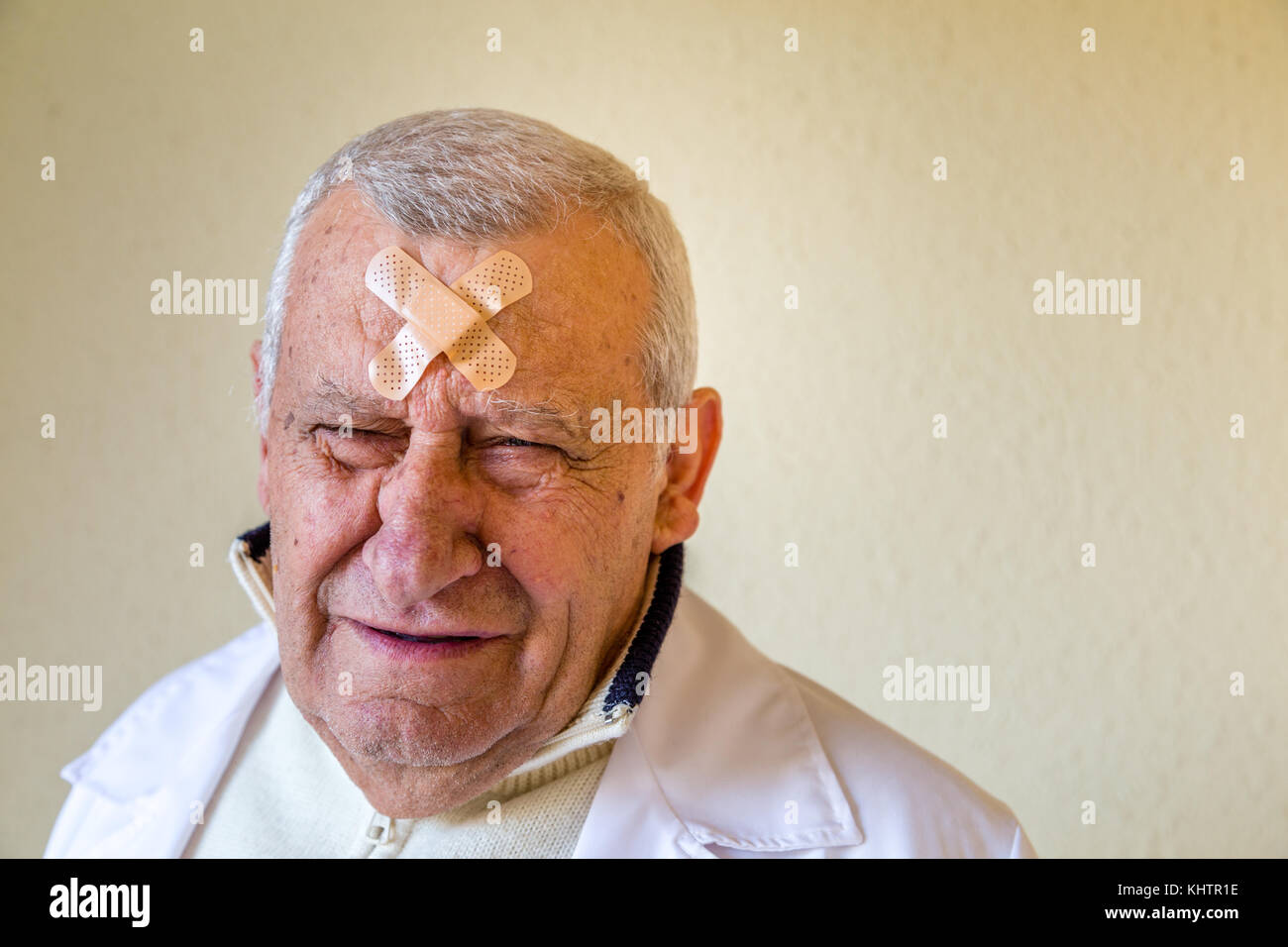 Triste vecchio medico con patch sulla fronte Foto Stock