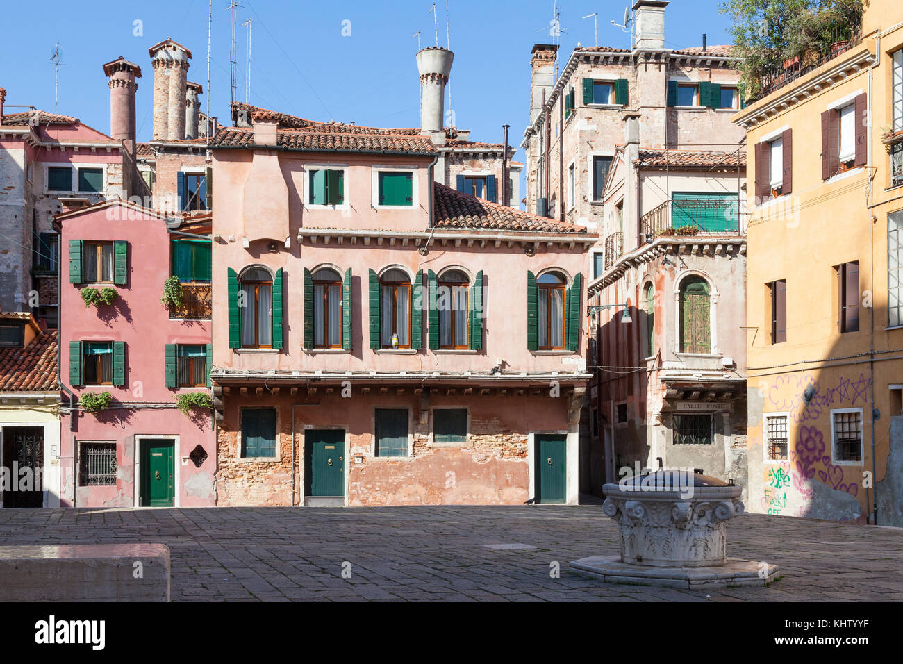 Colorate case medievali nel campo della Maddalena, Cannaregio, Venezia, Italia con una storica testa pozzo in primo piano e i tipici camini veneziano Foto Stock