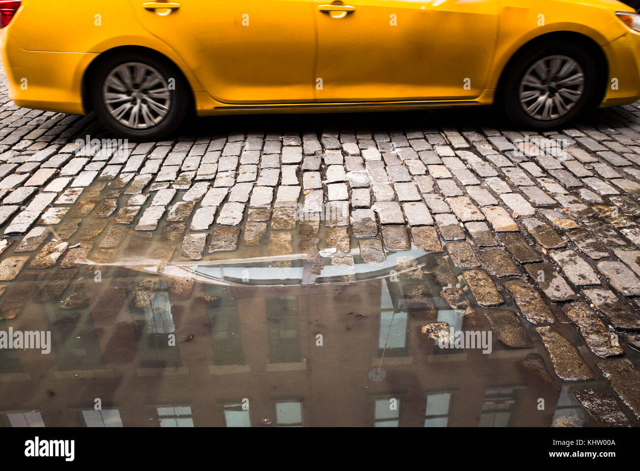 New York City strada di ciottoli con pozza e giallo taxi Foto Stock