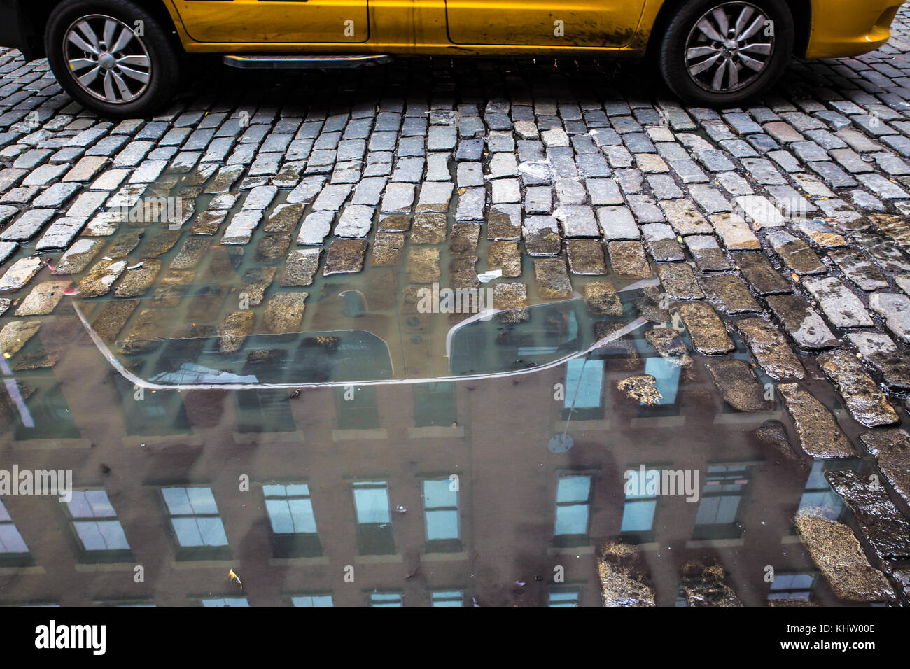 New York City strada di ciottoli con pozza e giallo taxi Foto Stock