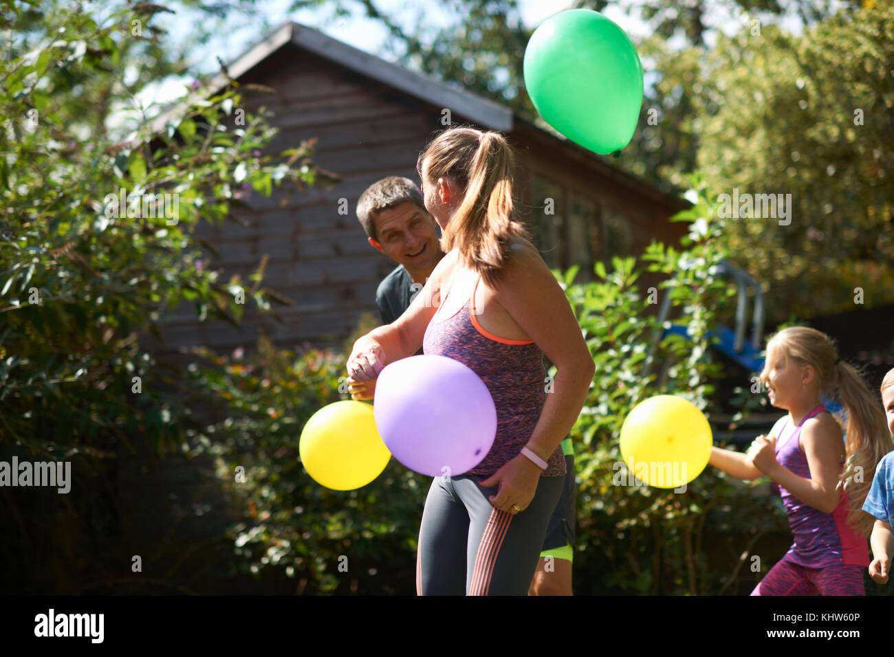 La famiglia gioca con palloncini in giardino Foto Stock