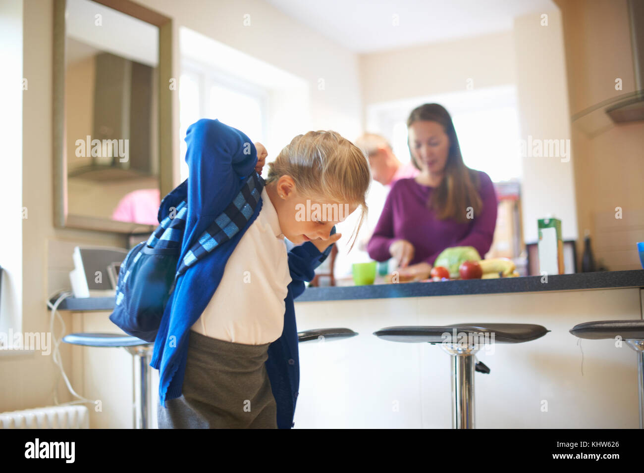 Schoolgirl mettendo su scuola sacchetta in cucina Foto Stock