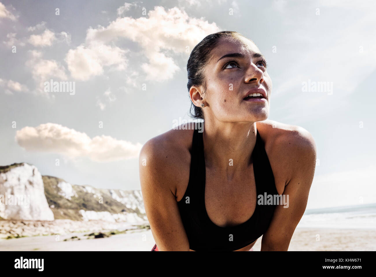 Esaurito giovane femmina runner prendendo una pausa sulla spiaggia Foto Stock