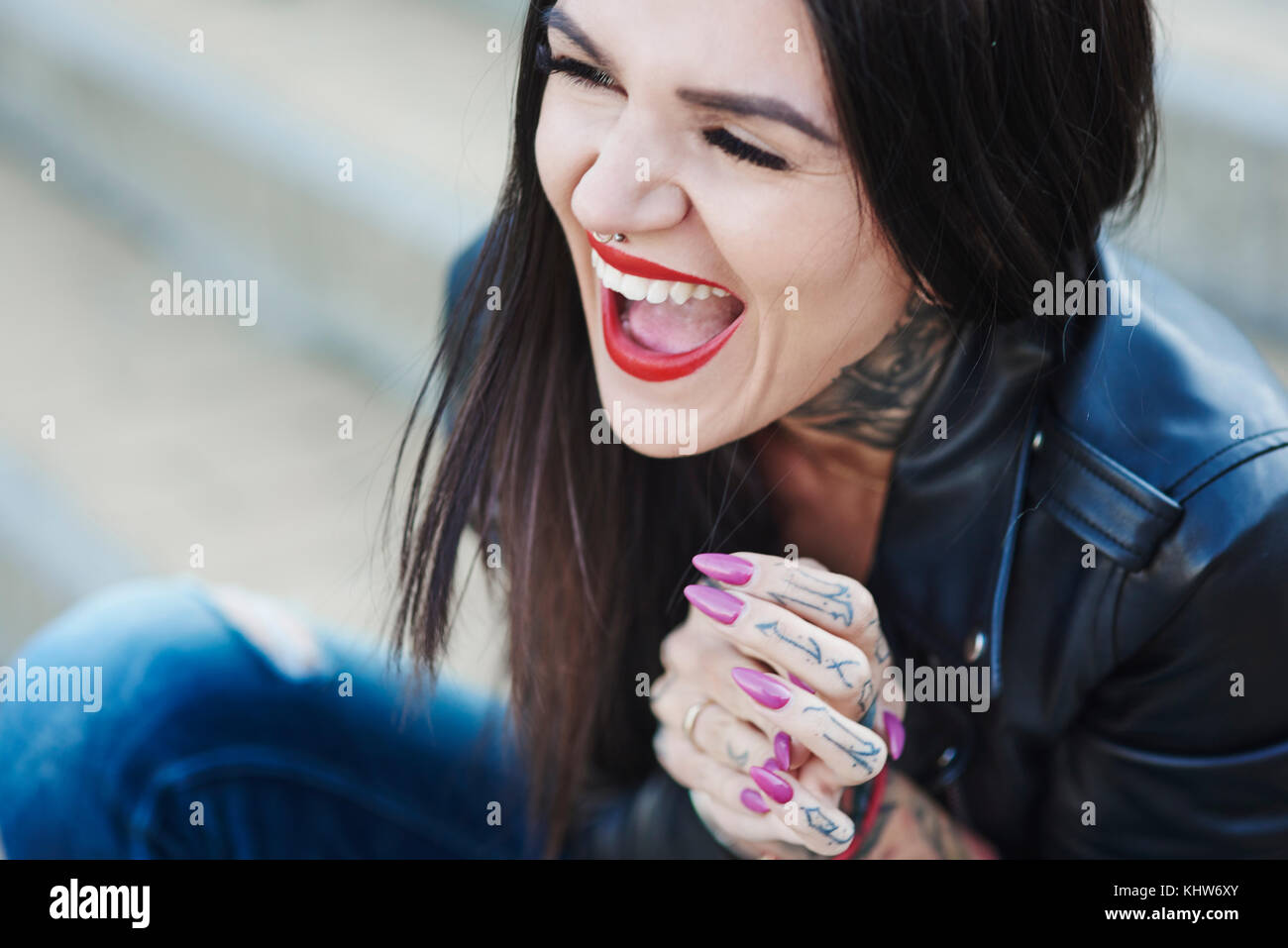 Ritratto di giovane donna di ridere, tatuaggi sul collo e canto Foto Stock