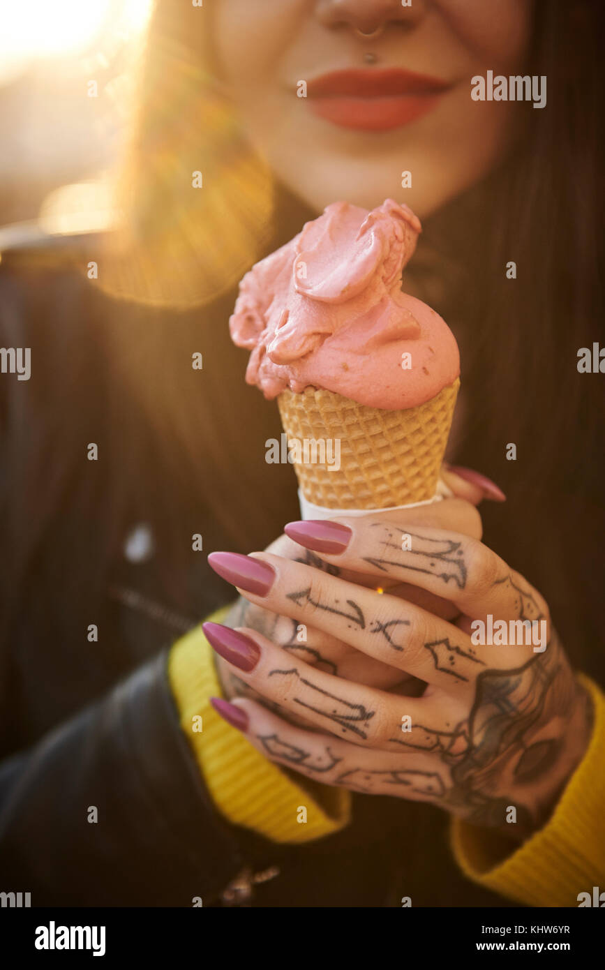 Giovane donna azienda gelato, tatuaggi sul canto, metà sezione, close-up Foto Stock