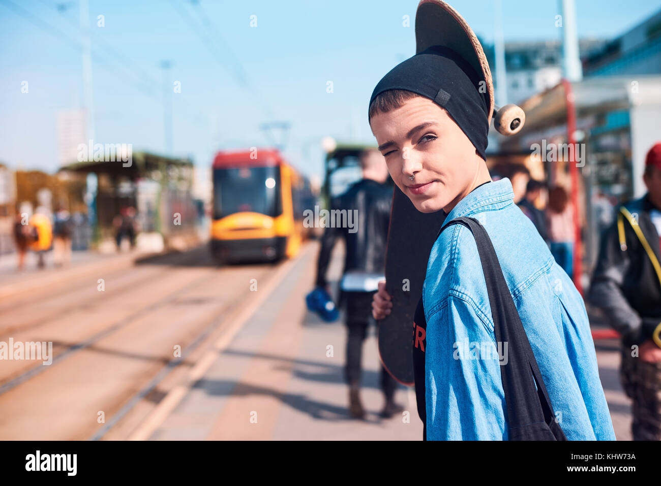 Ritratto di giovane donna guidatore di skateboard in beanie hat alla stazione del tram Foto Stock