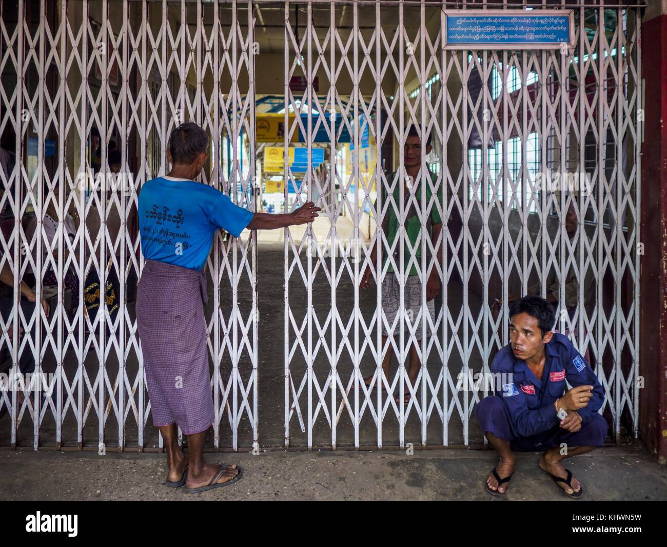 Yangon, regione di Yangon, Myanmar. 20 novembre 2017. Una guardia di sicurezza siede a terra di fronte all'uscita passeggeri al terminal dei traghetti di Dala. Decine di migliaia di pendolari prendono il traghetto ogni giorno. Porta lavoratori a Yangon da Dala, una comunità della classe operaia dall'altra parte del fiume da Yangon. È in corso la costruzione di un ponte sul fiume, a valle del traghetto per facilitare l'ingresso in città dei pendolari. Crediti: Jack Kurtz/ZUMA Wire/Alamy Live News Foto Stock