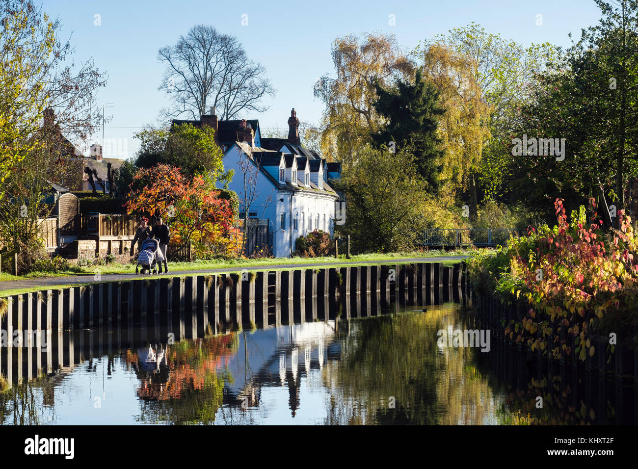 Paio di spingere un passeggino camminando sul canal alzaia in vigne Parco in autunno. Droitwich Spa, Worcestershire, Inghilterra, Regno Unito, Gran Bretagna Foto Stock