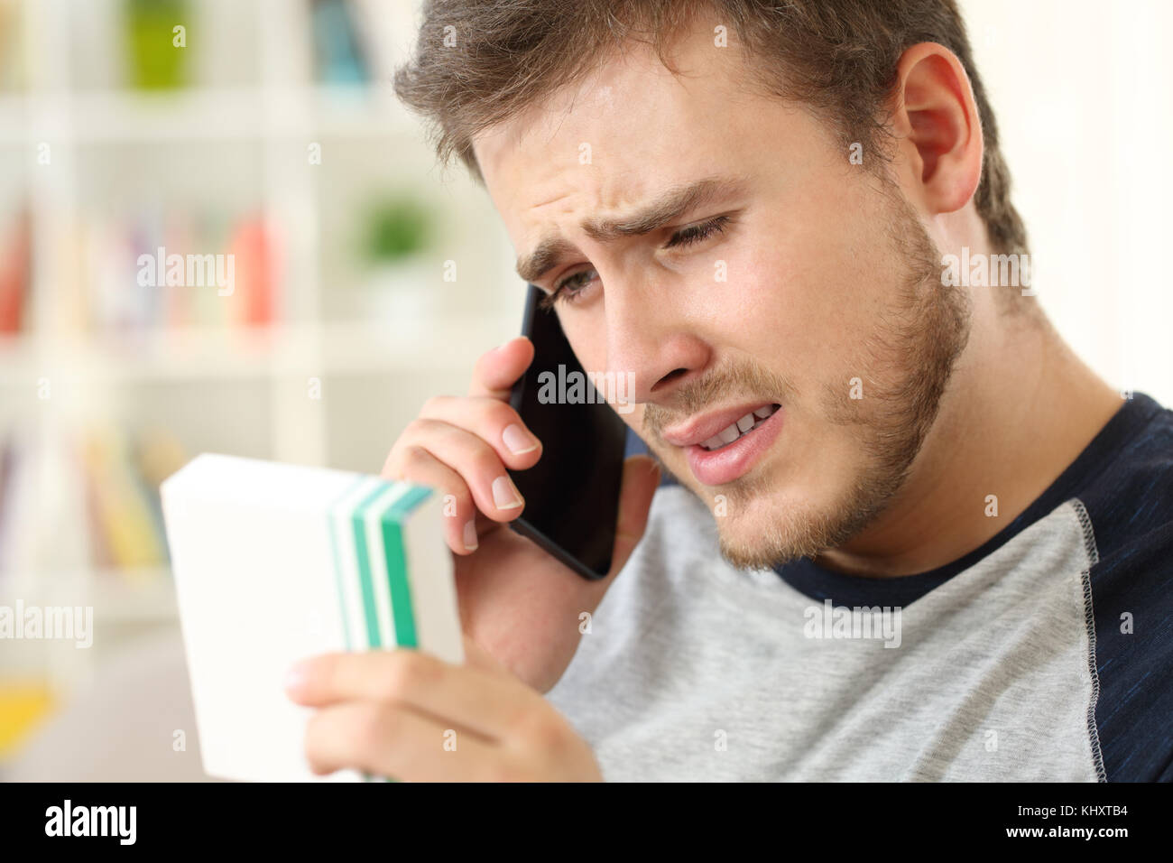 Preoccupato uomo medico di chiamata sul telefono chiedendo sui medicinali informazioni seduto su un divano a casa Foto Stock