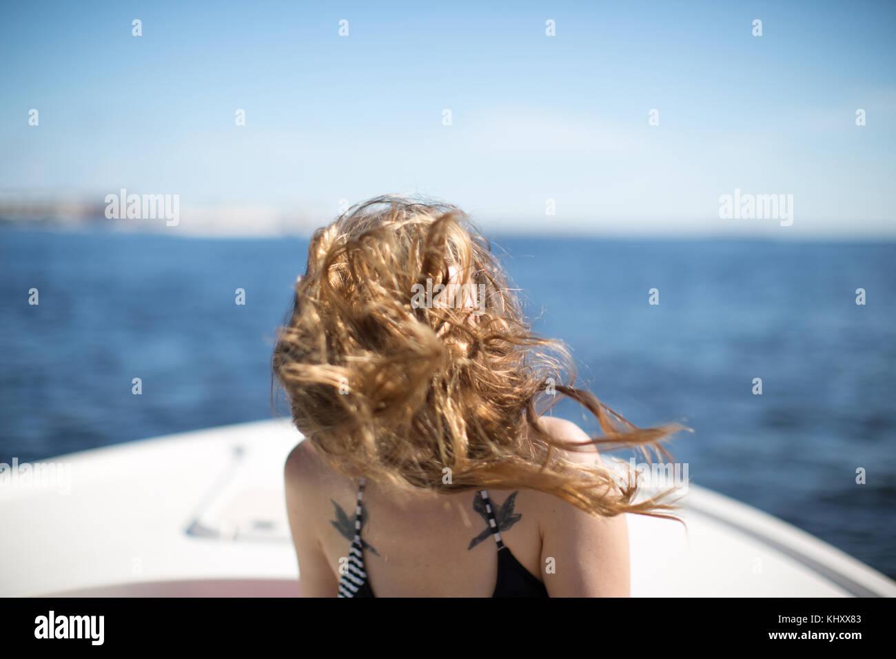 Donna sulla barca, capelli soffiando nel vento, che ricopre la faccia Foto Stock