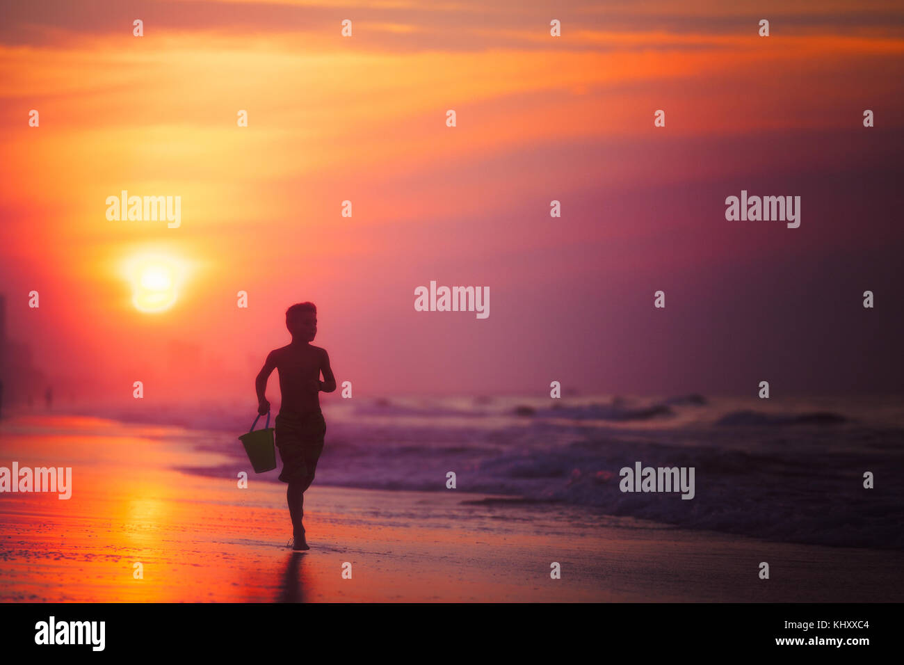 Silhouette di un ragazzo in esecuzione sulla spiaggia al tramonto, North Myrtle Beach, Carolina del Sud, Stati Uniti Foto Stock