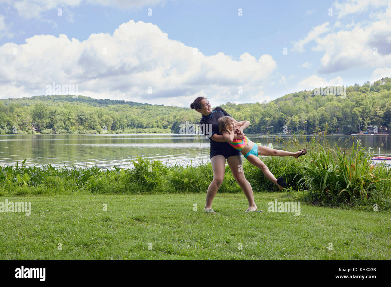 Oscillazione ragazza giovane ragazza intorno su erba, accanto al lago Foto Stock