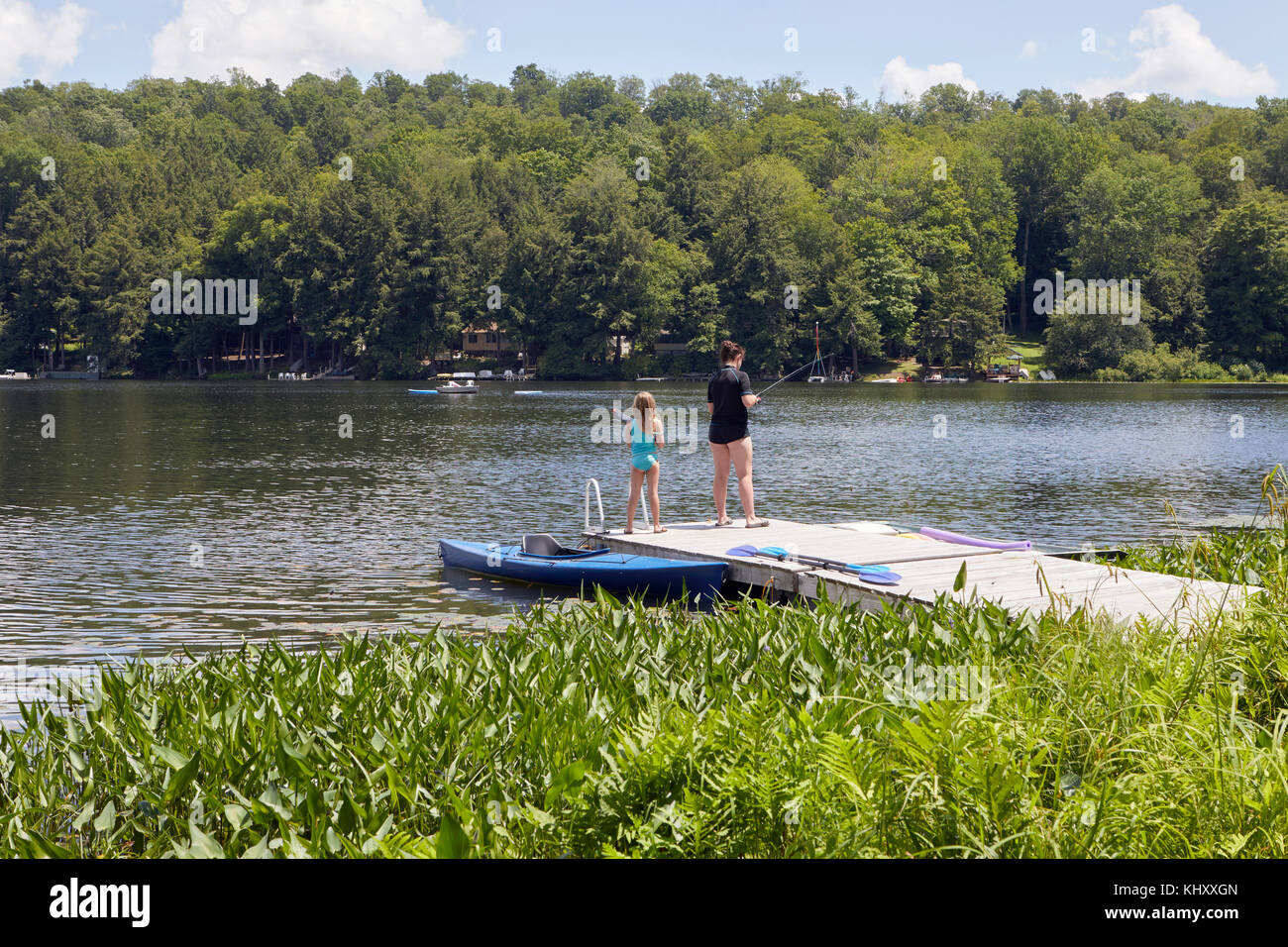 Due ragazze in piedi sul molo, pesca con canne da pesca Foto Stock