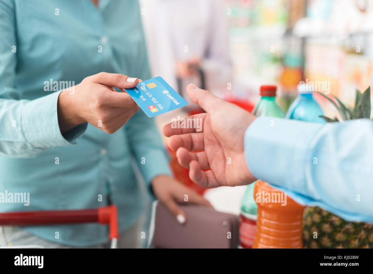 Donna al supermercato checkout, ella è dare la sua carta di credito per il cassiere, retail e il concetto di pagamenti Foto Stock