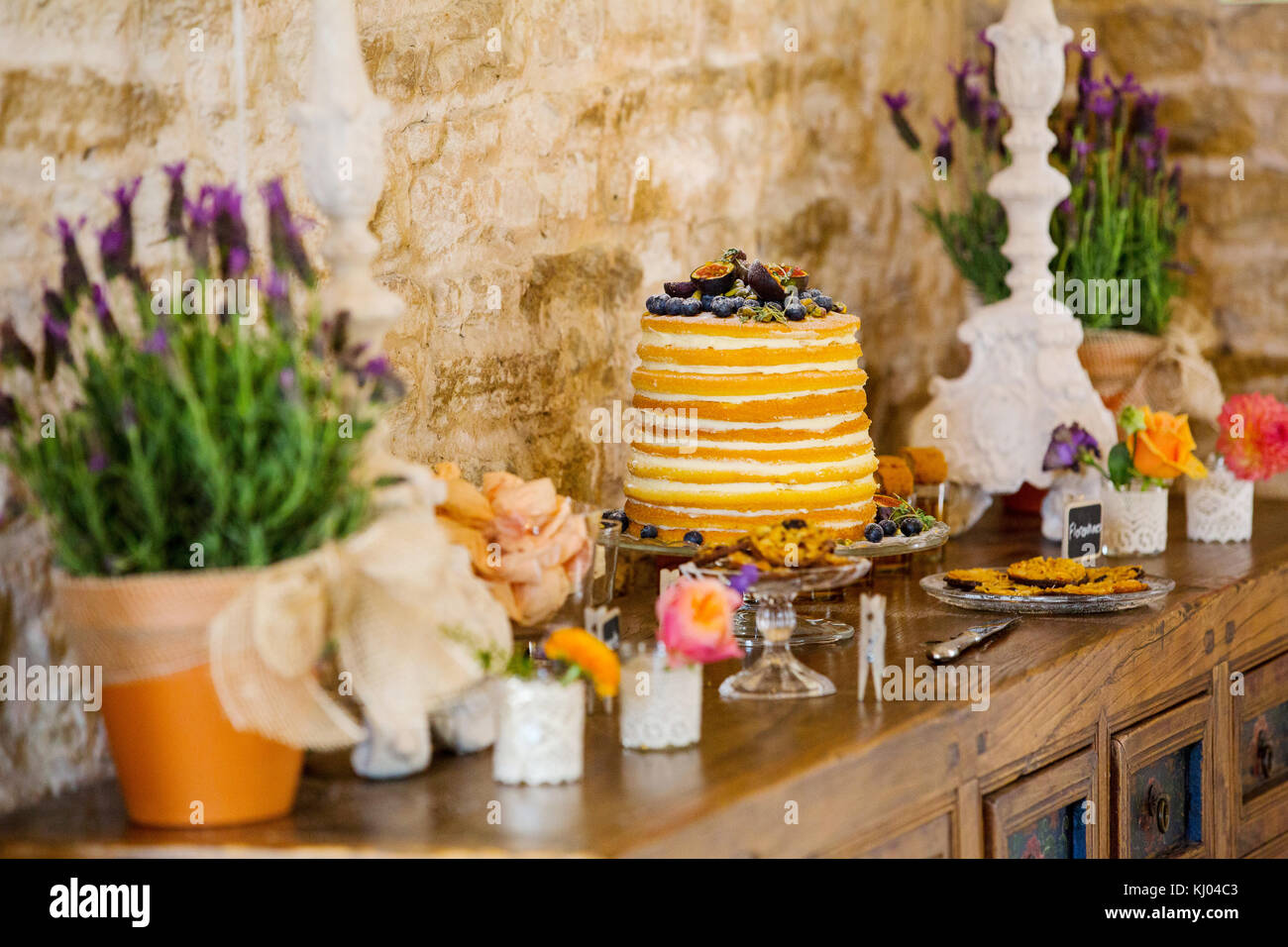 Layered torta nuziale con fiori e i biscotti sulla sponda al ricevimento di nozze Foto Stock