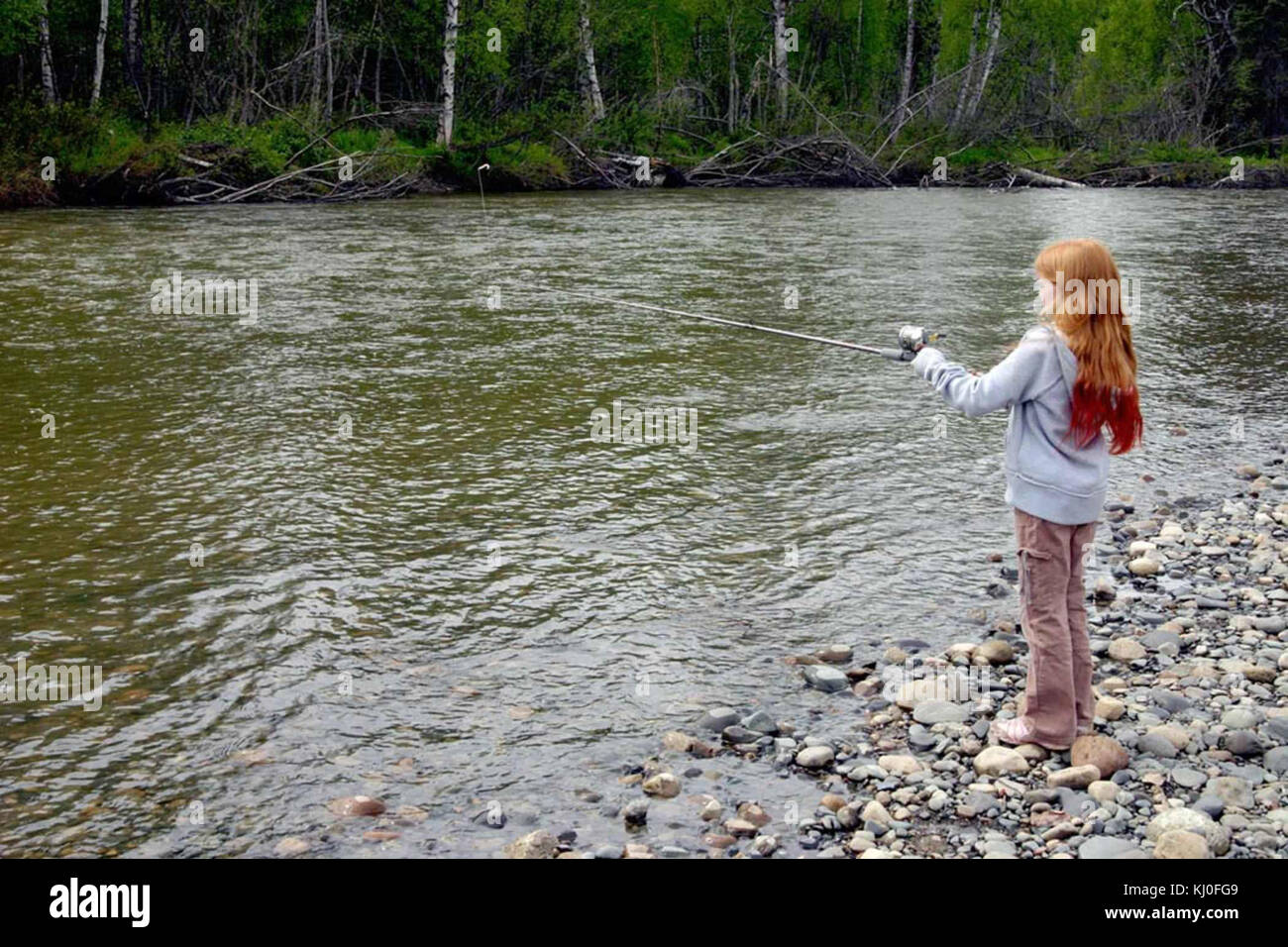 Una fotografia di una ragazza in piedi sulla riva, che pesca con una canna, che cattura un momento tranquillo all'aperto, forse dell'inizio del XX secolo. Foto Stock