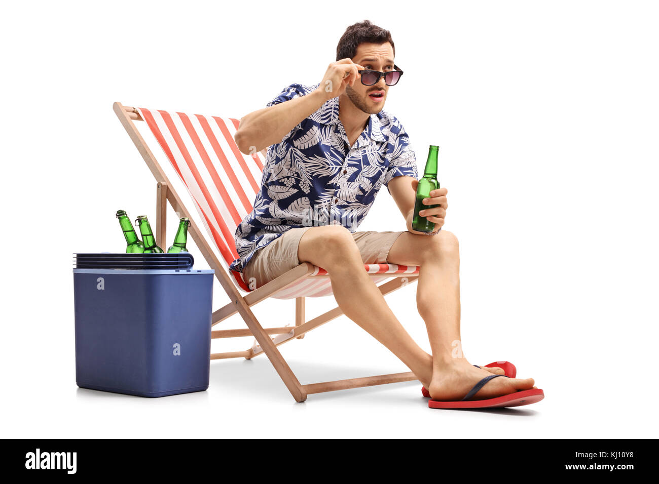 Stupito turistico con una bottiglia di birra seduto in una sedia a sdraio e fissando sopra i suoi occhiali da sole isolato su sfondo bianco Foto Stock