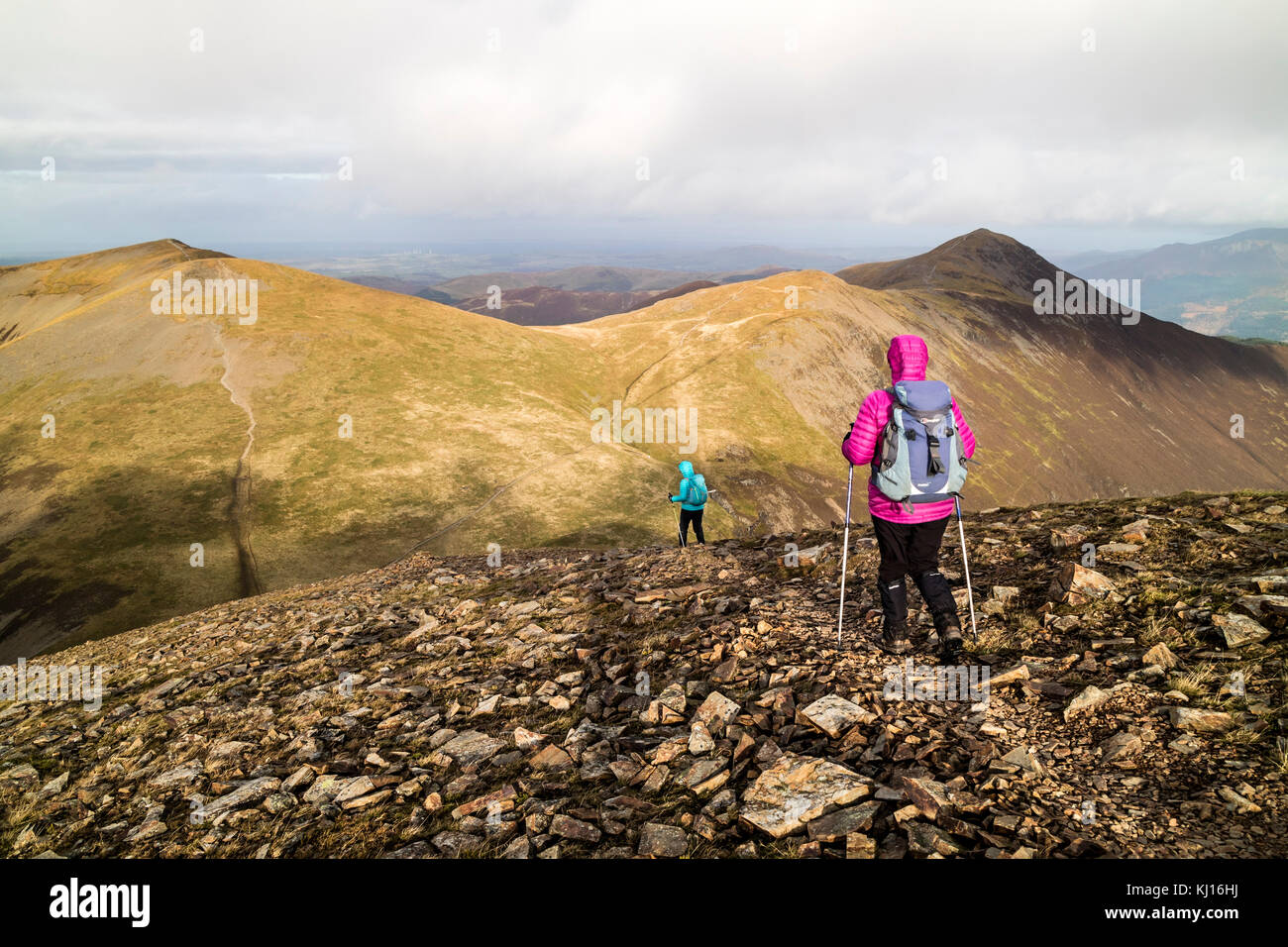 Due escursionisti rupe discendente Collina con i picchi di Sand Hill, Hopegill Testa e Grisedale Pike, davanti, Lake District, Cumbria Regno Unito Foto Stock
